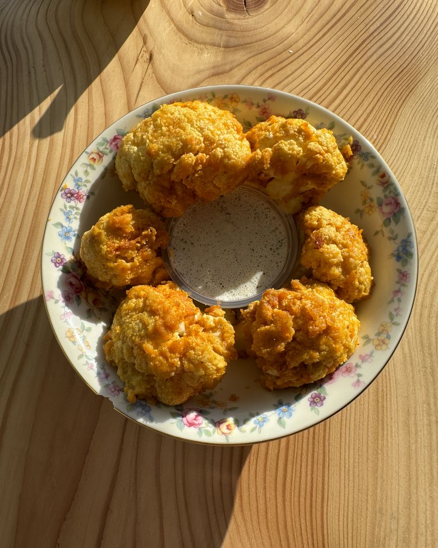 Golden cauliflower bites around a bowl of creamy dip