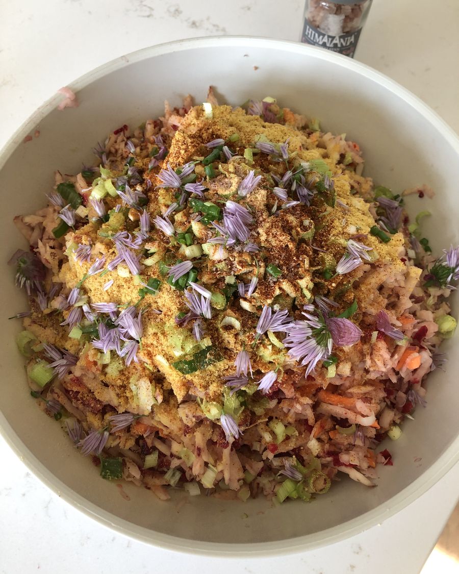 A large bowl of shredded vegetable salad topped with chive blossoms