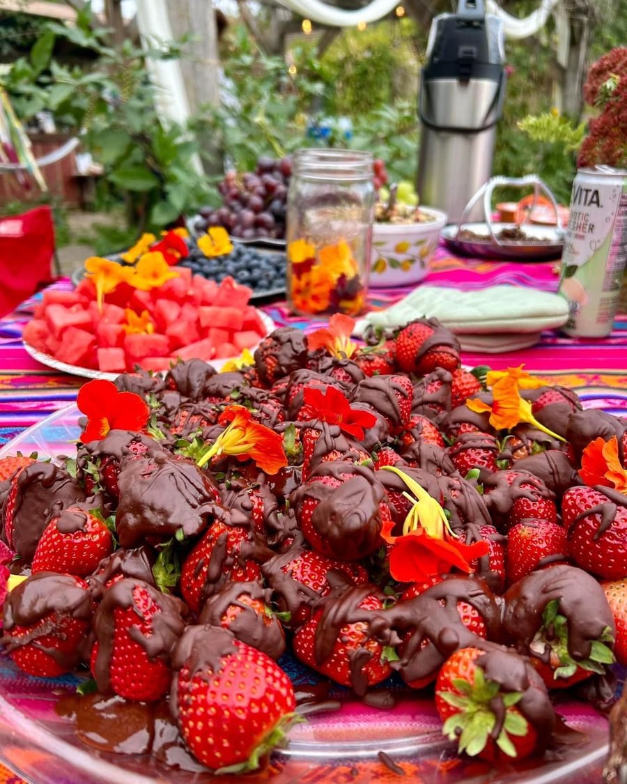 Chocolate-dipped strawberries scattered with nasturtium blossoms on an outdoor table